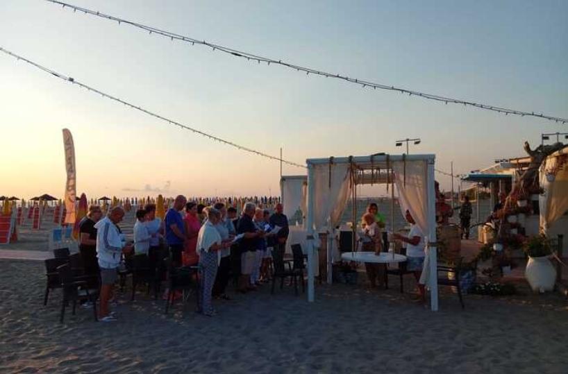 A Margherita di Savoia un sacerdote benedice i nonni all'alba in spiaggia
